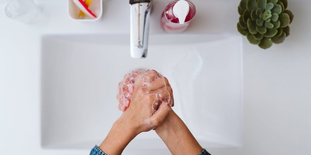Top view of hands washed with soap at a clean sink, highlighting hand hygiene's role in a health-conscious lifestle.